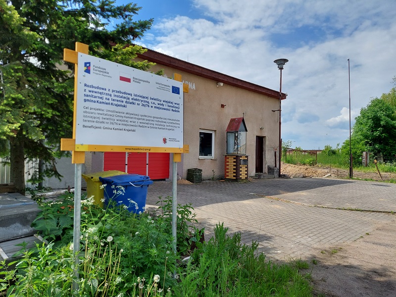 Świetlica w Radzimiu przed rozbudową; ławy fundamentowe; tablica informacyjna