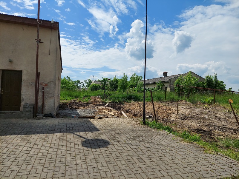 Świetlica w Radzimiu przed rozbudową; ławy fundamentowe; tablica informacyjna